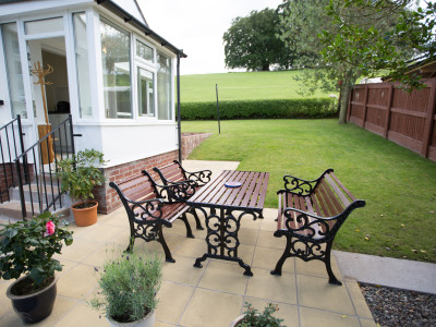 “Sunny patio with garden seating at Wall & Lakes Holiday Cottage, Brampton, Cumbria